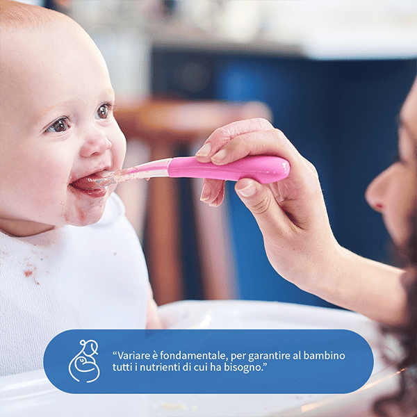 Bambino che riceve cibo con cucchiaio da un caregiver.