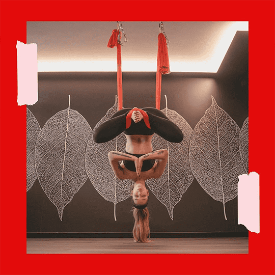 Donna che esegue yoga acrobatica su anelli sospesi in studio moderno.